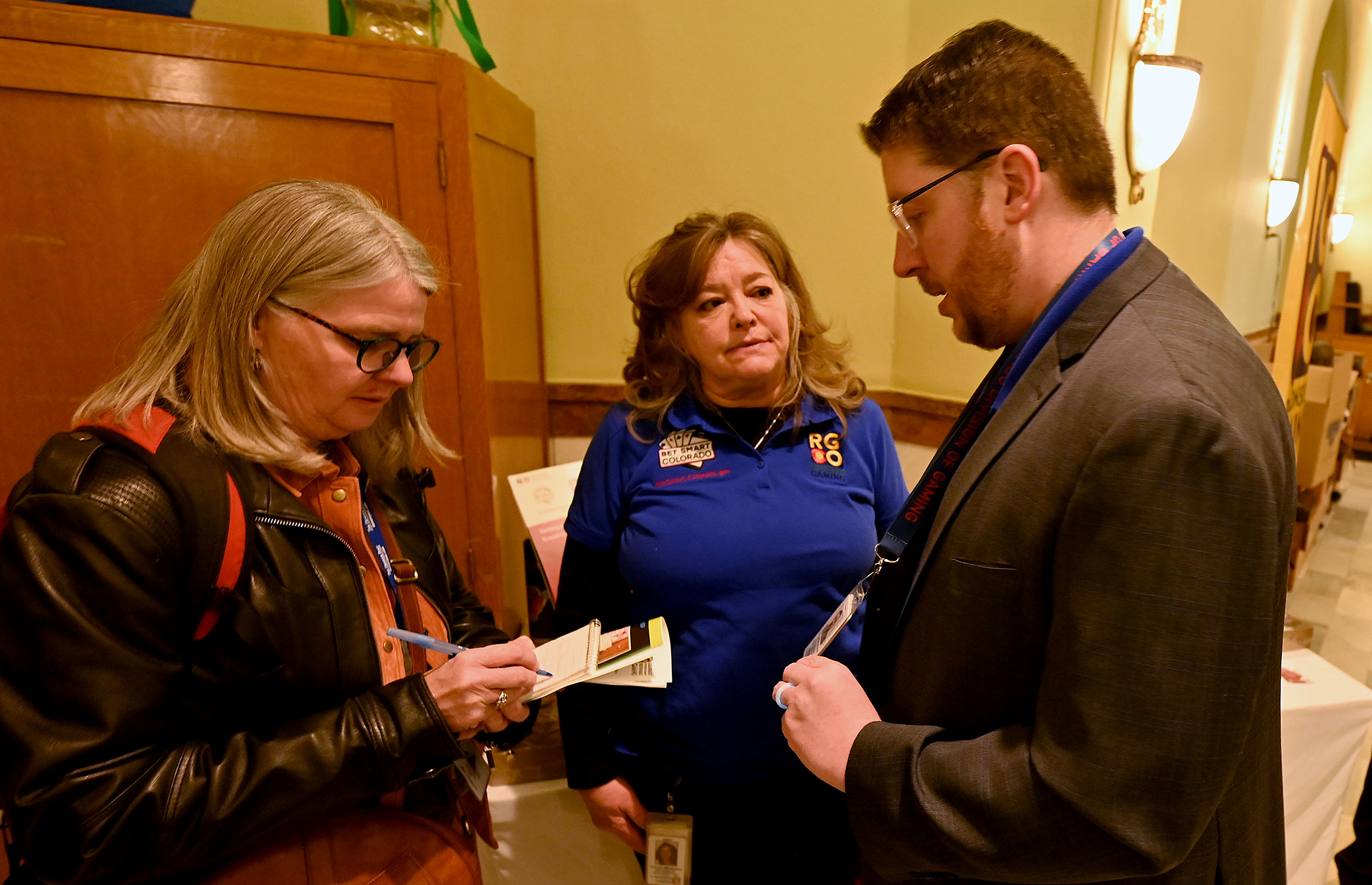 Colorado Division of Gaming Director Christopher Schroder (right) and Responsible Gaming Manager Corrie Martinez (middle) speak with a reporter about problem gambling awareness on Wednesday, Feb. 26, 2025 at the state capitol in Denver.The Colorado Division of Gaming and the Colorado Lottery, both divisions of the Colorado Department of Revenue, raised problem gambling awareness inside the state capitol in Denver as part of Problem Gambling Awareness Day. Staff members shared problem gambling resources with lawmakers and statehouse visitors in an effort to highlight Problem Gambling Awareness Month. (Derek Kuhn/CDOR Photo)